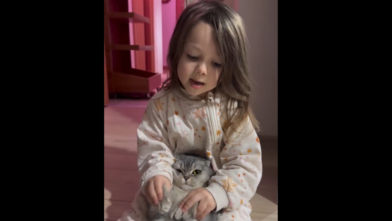 Child sings while holding cat in Istanbul, Türkiye