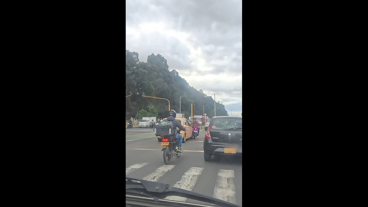 Motorcycle rider avoids falling after collision in Bogotá, Colombia