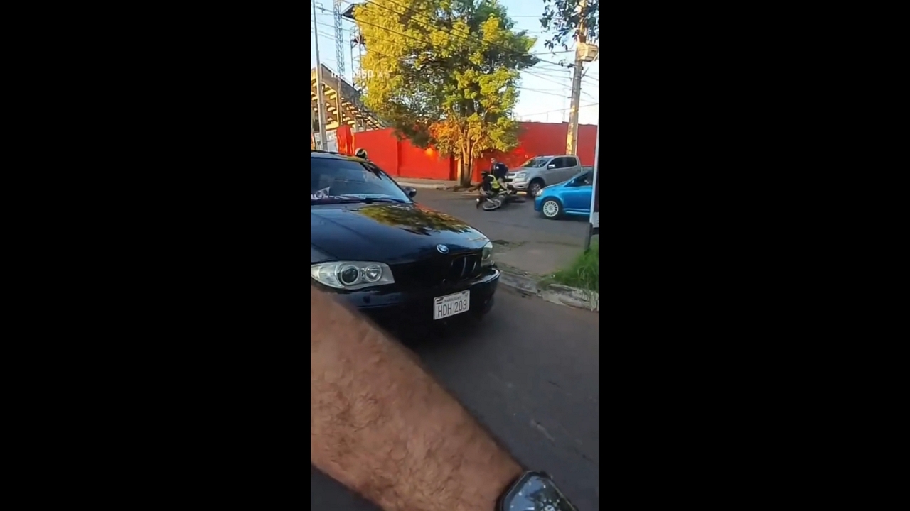 Motorbike narrowly avoids collision at intersection before riders fall in Asunción, Paraguay