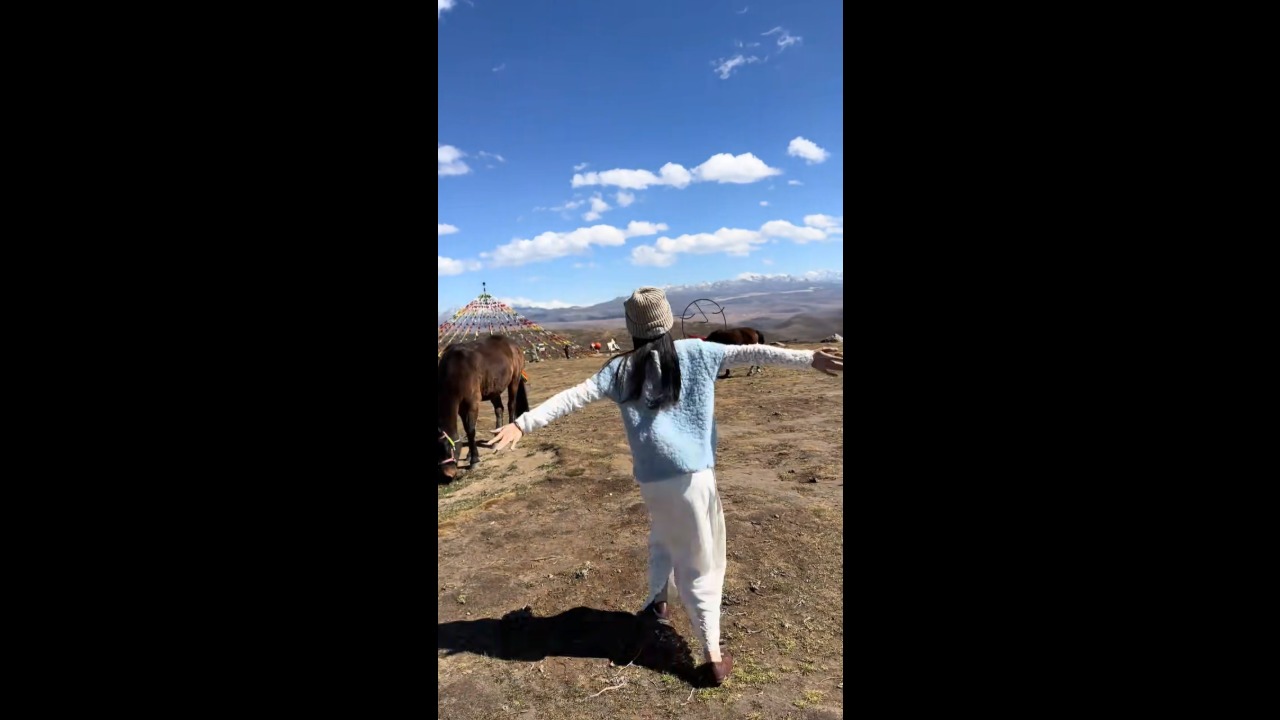 Woman gets startled when horse suddenly kicks at her in a grassy field in Sichuan, China