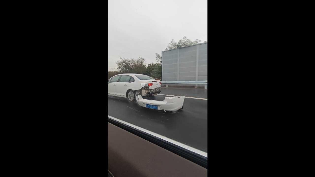 Car drives along a highway with a broken rear bumper dragging behind in Jiangsu, China