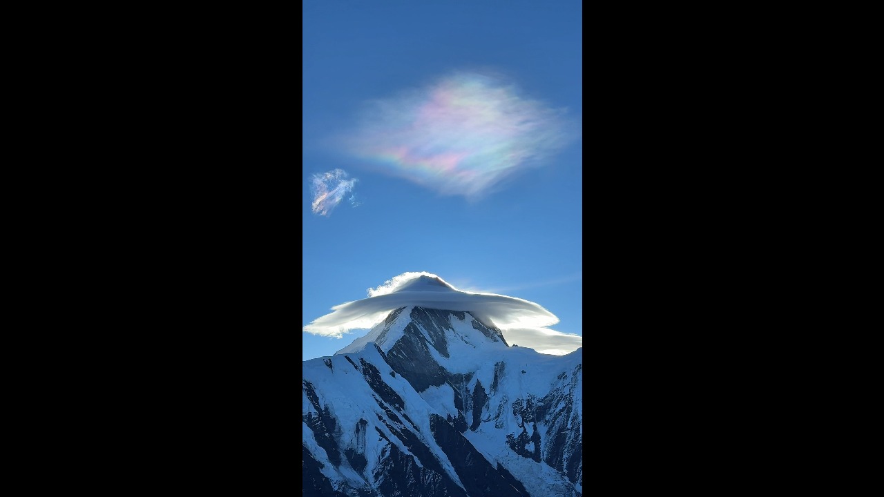 Hikers amazed by colorful lenticular cloud forming above a snow-capped mountain in Sichuan, China