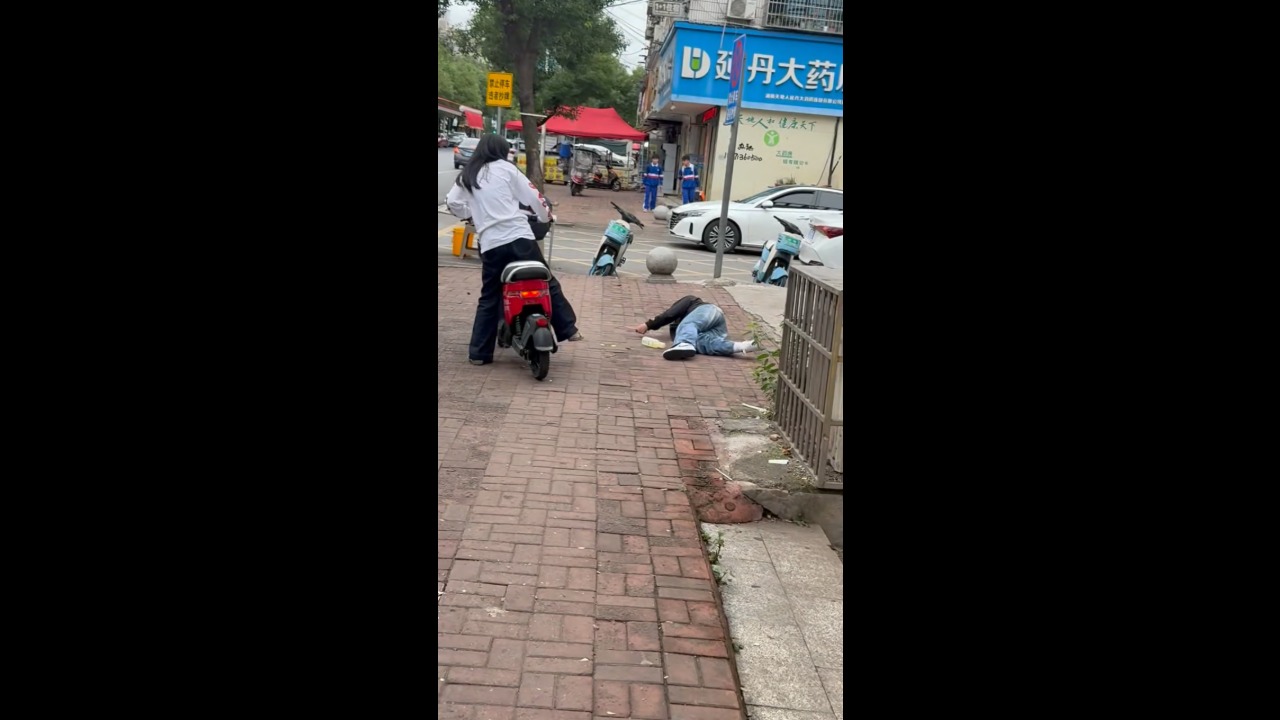 E-bike passenger loses balance and falls after dragging foot along sidewalk in Hunan, China