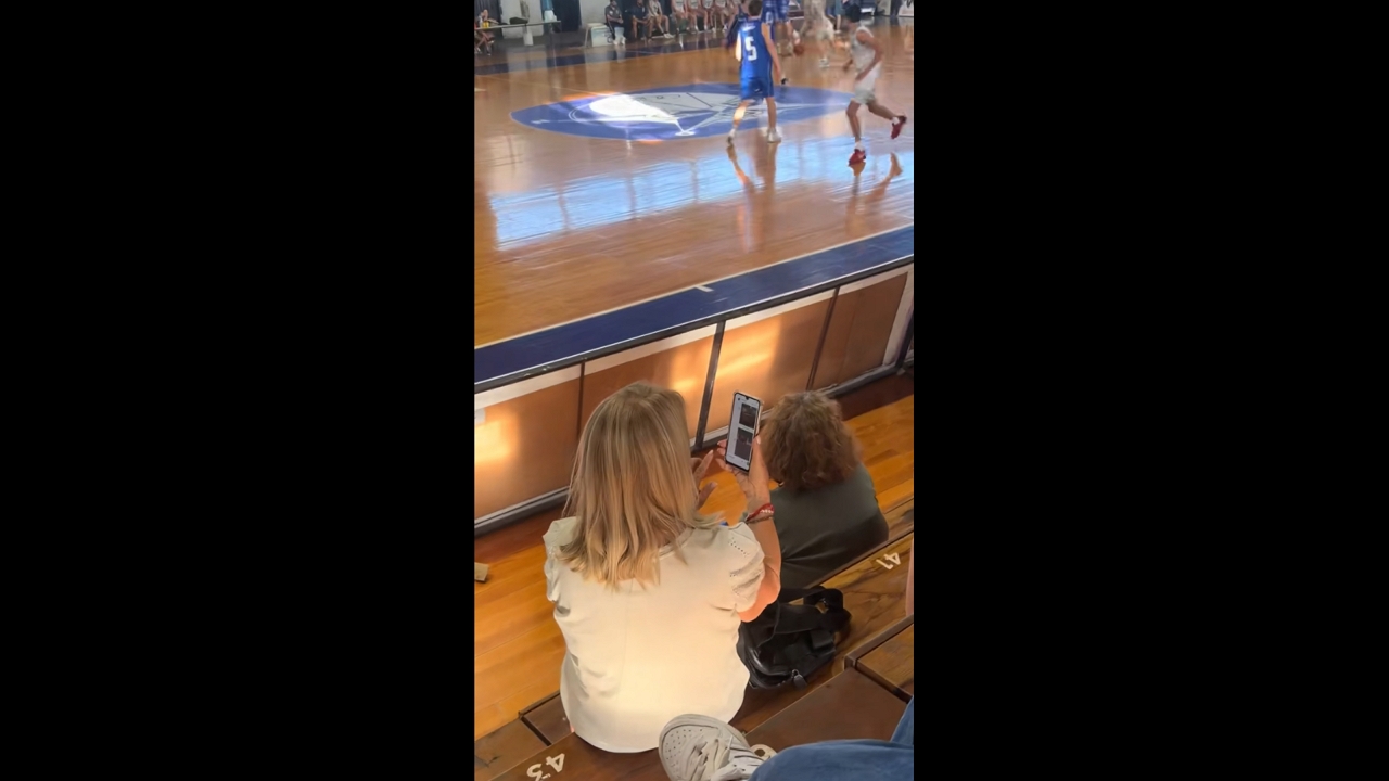 Woman struggles with phone camera during basketball match in Concepción del Uruguay, Argentina