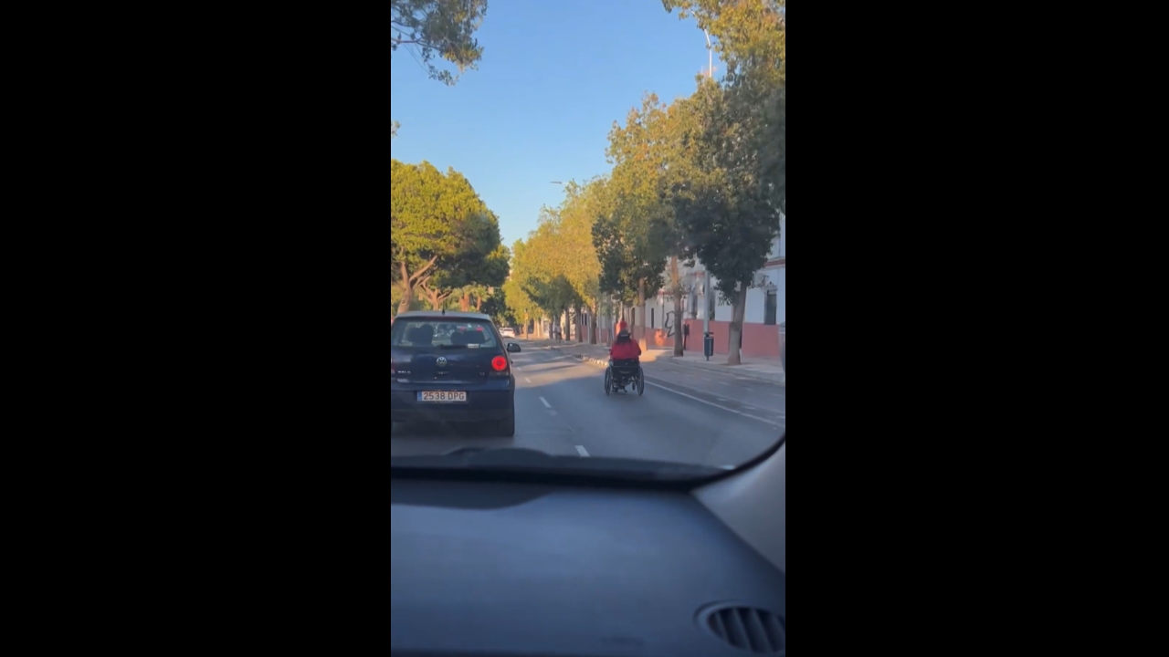 Person in wheelchair moves at high speed on road in Málaga, Spain