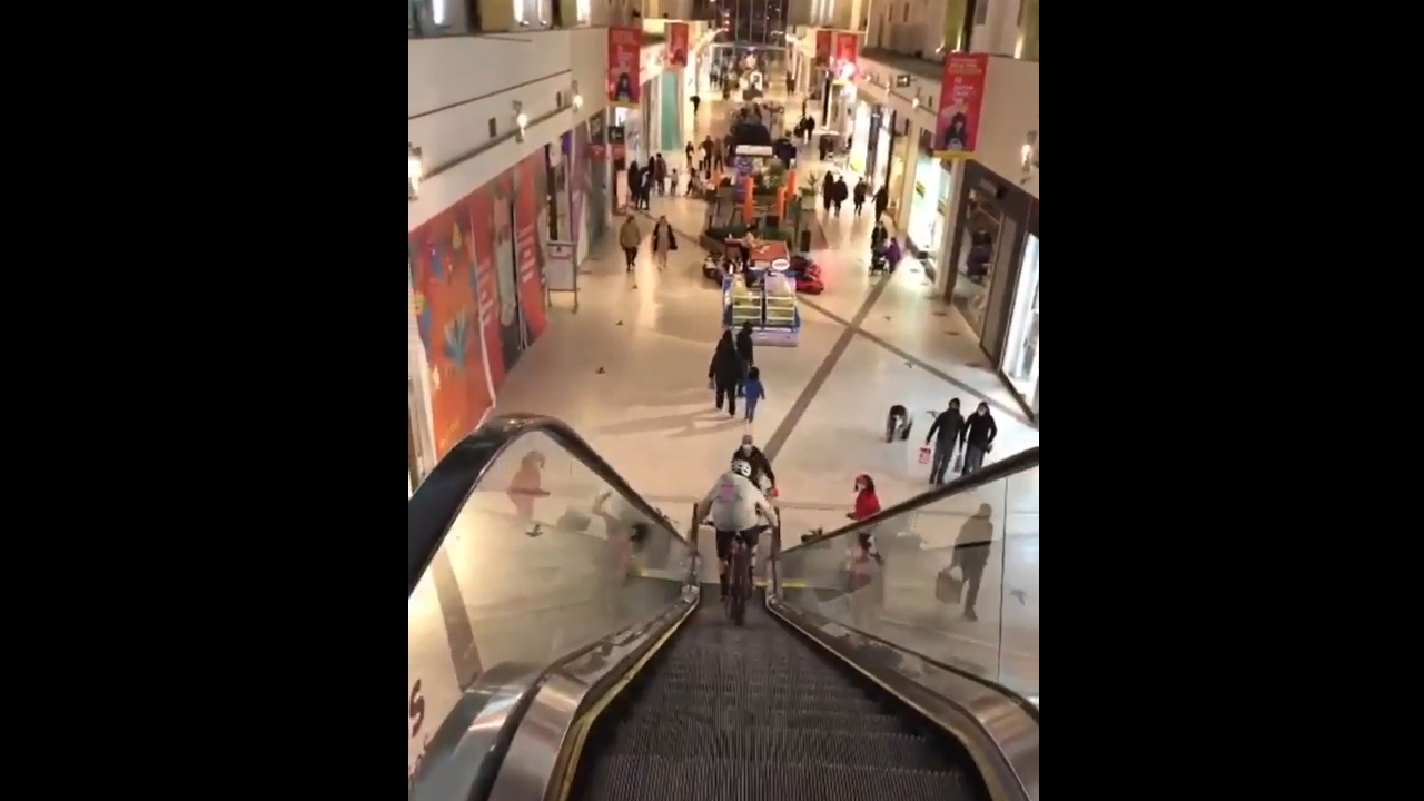 Person rides bike down moving escalator in Concepción, Chile