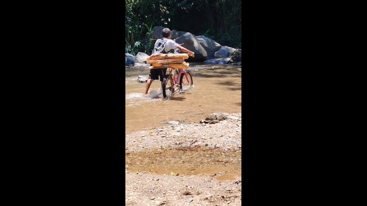 Boy and dog carefully cross stream with bicycle in Sendero La Montañita, Argentina
