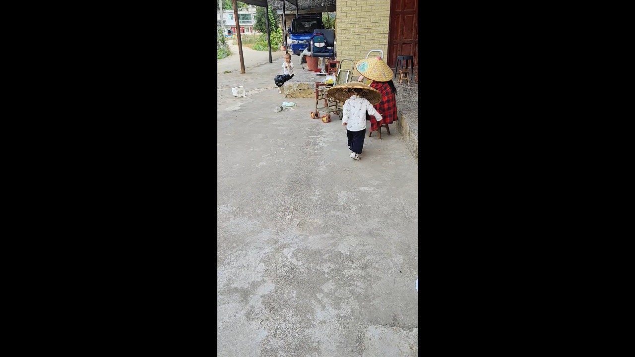 Little boy wearing an oversized bamboo hat bumps into an elderly person in Guizhou, China
