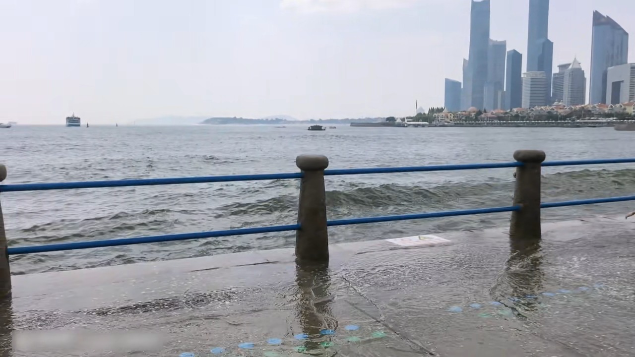 Powerful wave crashes over seaside barrier and drenches child near the shore in Qingdao, China