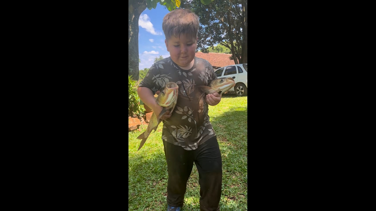 Boy proudly carries two large fish in Doutor Maurício Cardoso, Brazil