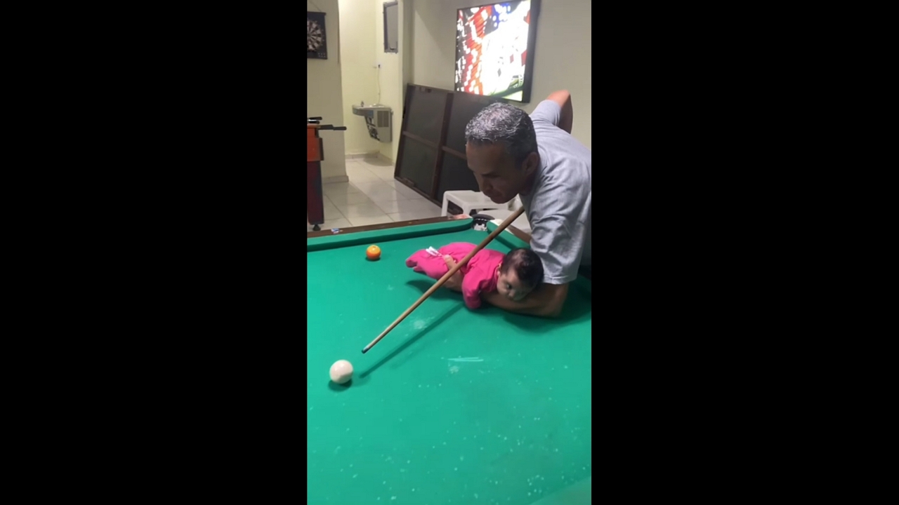 Grandpa uses baby as pool cue support in Itanhaém, Brazil