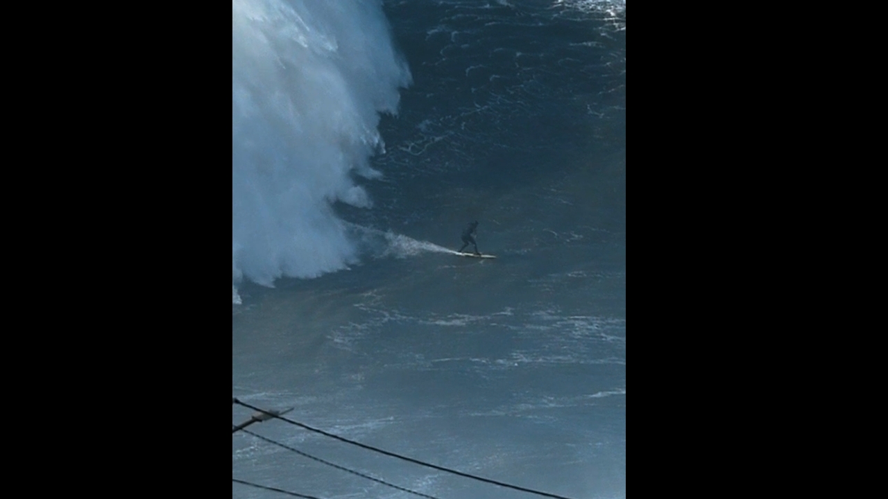 Surfer rides massive wave as spectators watch in Nazaré, Portugal