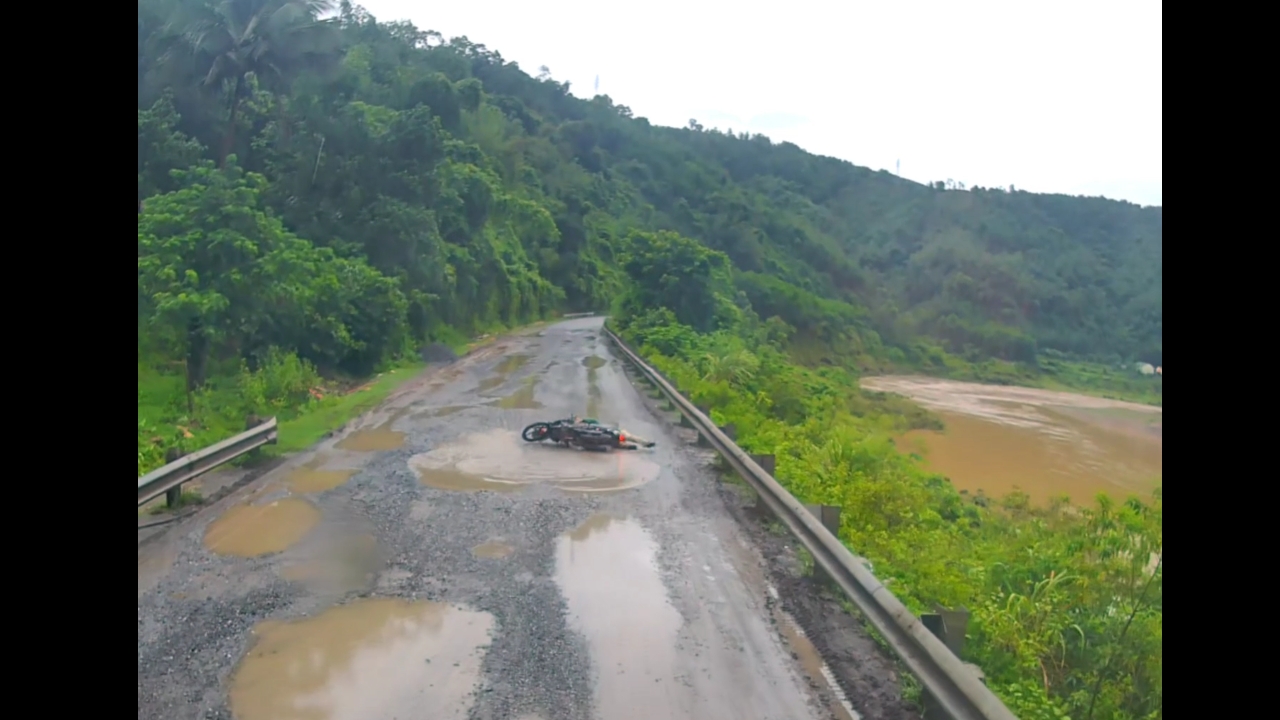 Motorbike rider falls into puddle on pothole-ridden road in Quảng Trị, Vietnam