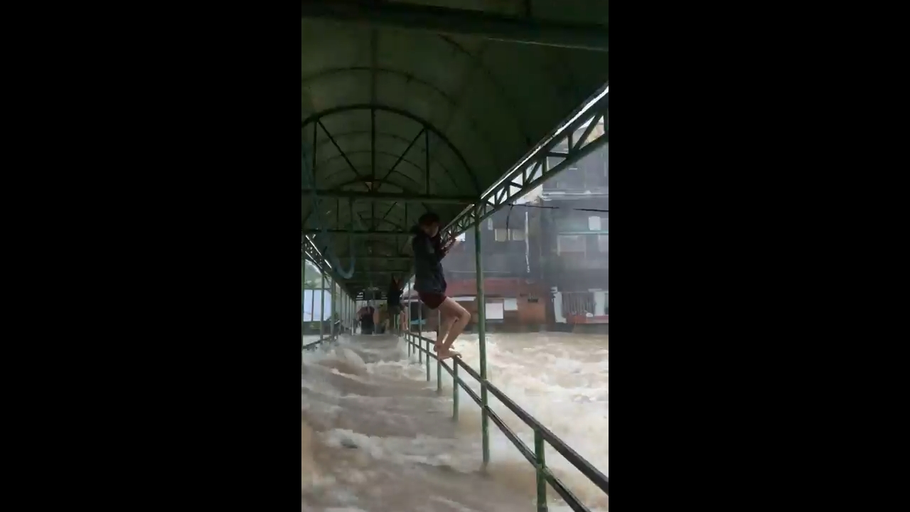 Residents climb bridge railings to escape floods in Cabagñan, Philippines