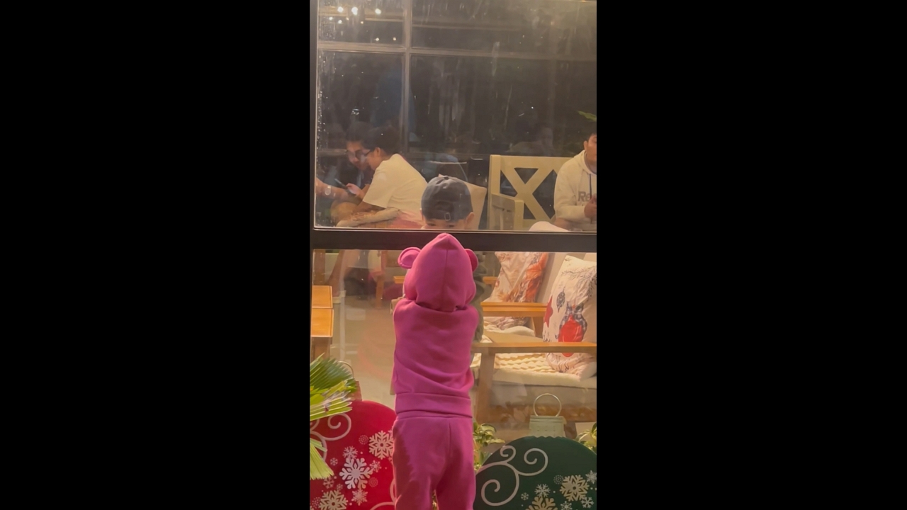 Girl and boy share playful moment through café glass in Mabitac, Laguna, Philippines