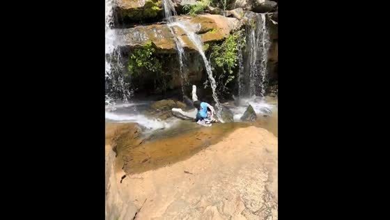 Person slips while walking under a waterfall in Kenya