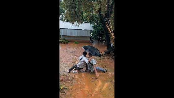 Friends slip and fall on muddy slope in Sidoarjo, Java, Indonesia