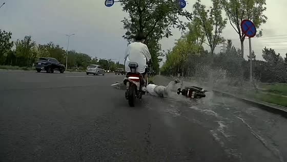 E-bike rider slips on puddle and crashes into road barrier in Beijing, China