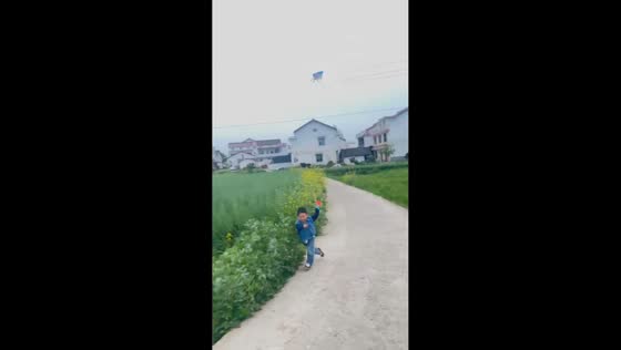 Boy trips while running with kite on roadside in Shaanxi, China