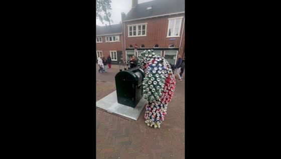 Street performer in can-covered suit entertains pedestrians in Harlingen, Netherlands