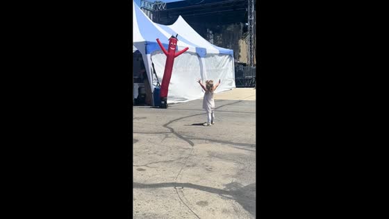 Girl mimics dancing tube man at county fair in Sacramento, California, USA