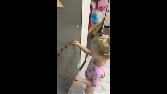 Little girl playfully sticks marmalade to fridge in Hrodna, Belarus