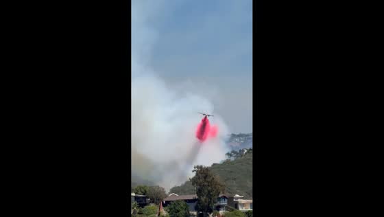 Aircraft drop water amid thick smoke during Laguna Beach fire in California, USA