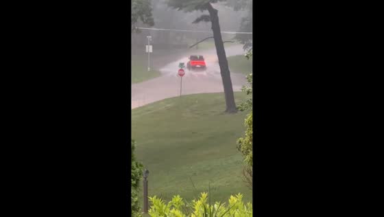 Vehicle drives through flooded road during intense storm in Moline, Illinois, USA