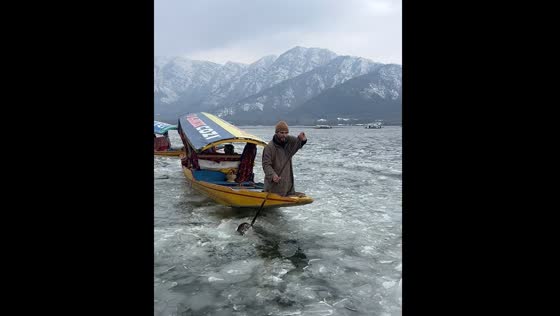 People row boats in frozen Dal Lake in India