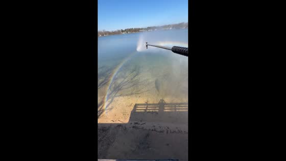 Pressure washer creates rainbow by lakeside in Grand Rapids, Michigan, USA