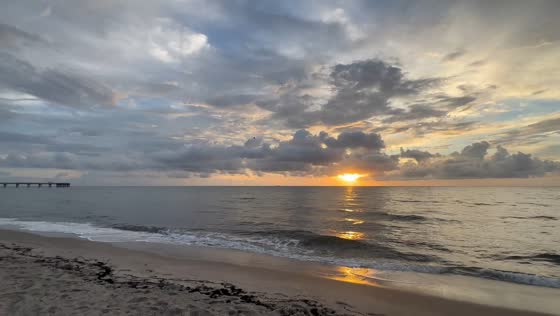 Golden sunrise breaks through dramatic clouds over Atlantic Ocean in Dania Beach, USA