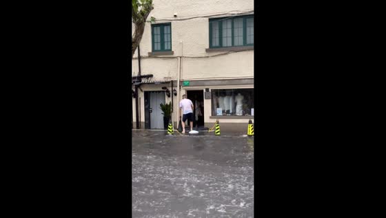 Man places sandbags as floodwaters cover Xinle Road in Shanghai, China