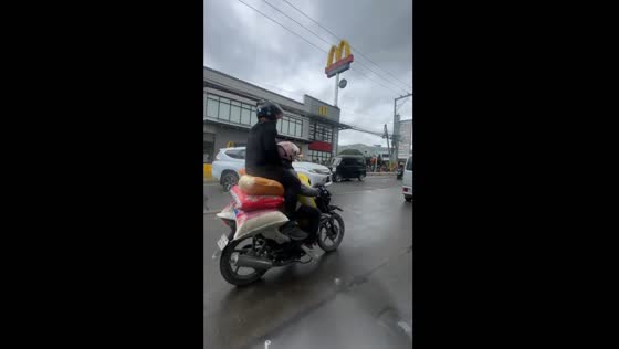 Motorcycle passenger sits on luggage in Manila, Philippines