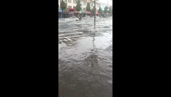 Cyclists ride through flooded street in Shandong, China