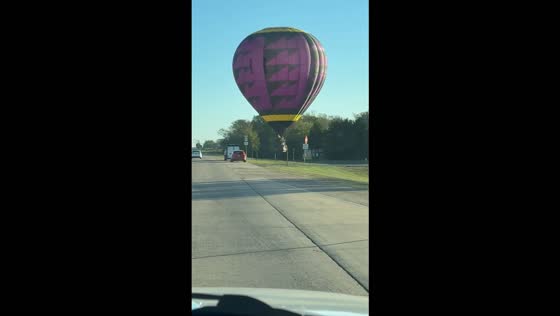 Low-flying hot air balloon drifts across a highway in Poteau, USA