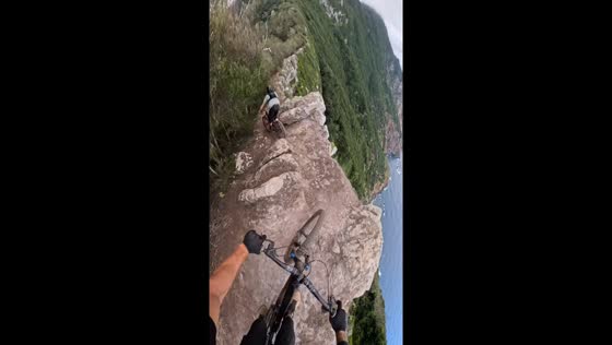 Mountain bikers navigate narrow cliffside trail in Funchal, Portugal