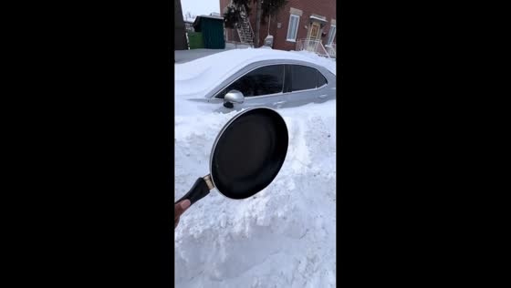 Woman uses frying pan to clear snow from car in Montreal, Canada