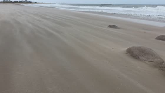 Blowing sand and powerful surf batter East Beach during nor’easter in Charlestown, USA