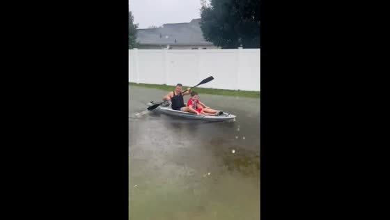 Father and son row boat through flooded road in Longs, South Carolina