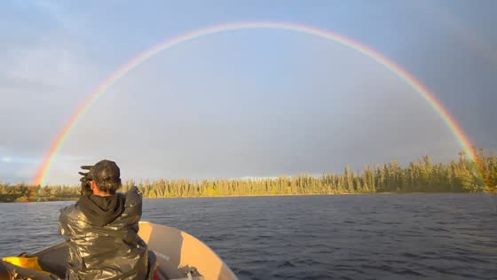 Vivid full rainbow stretches across sky over Pickle Lake in Ontario, Canada