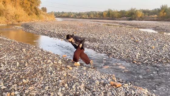 Woman trips and falls while jumping over a stream in Xinjiang, China