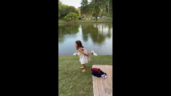 Girl mimics ducks by the lake in Bali, Indonesia
