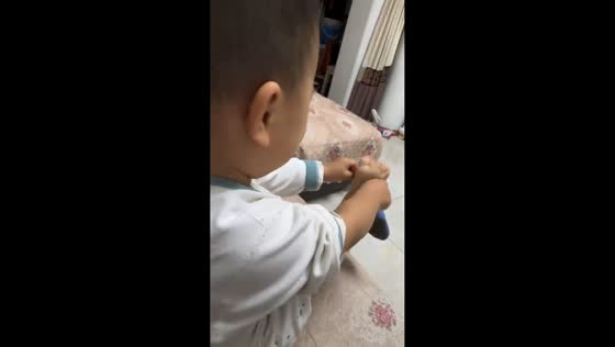 Frustrated child hits leg while struggling with sock in Shaanxi, China