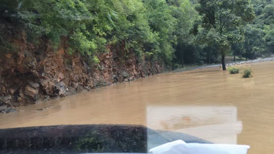 Overflowing river floods winding forest road in Shangluo, China