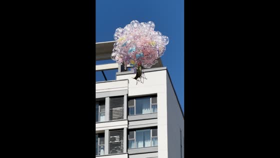 Cluster of balloons lifts a chair high above nearby buildings in Tangshan, Hebei, China