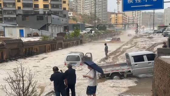 Car drives through heavily flooded road in Shanxi, China