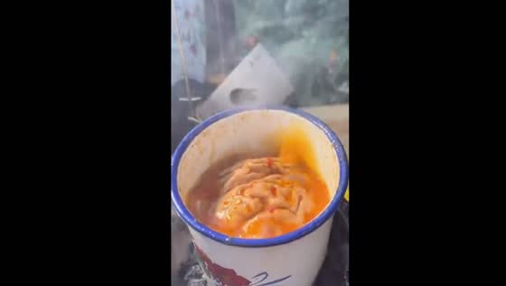 Traditional Chinese cuisine: cooking and enjoying pig's brain in an iron cup