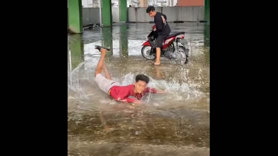 A group of friends stumble and fall on a slippery road in Indonesia