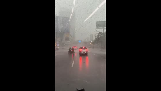 Motorcyclists struggle through heavy rain and strong winds in Surabaya, Indonesia