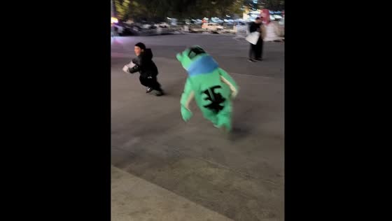 Child runs crying after being chased by another in frog costume